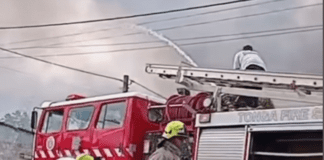 Onlookers mock firefighter as he wrestles to direct fire hose at raging fire